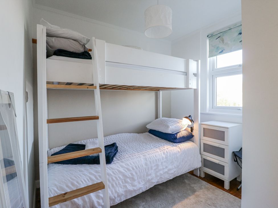 A bedroom with a bunk bed and twin bed at Beachside Terrace in Harwich