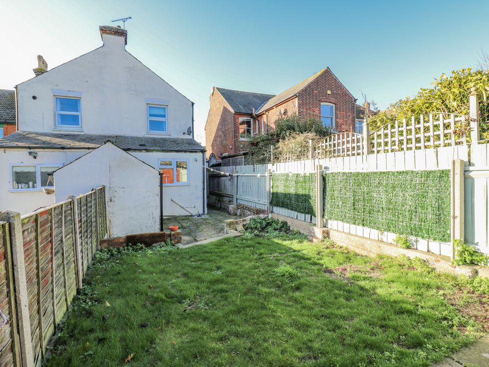 A garden with grass and a fence at Beachside Terrace in Harwich