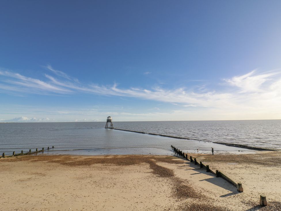 A beach with a pier extending into the water at Beachside Terrace in Harwich