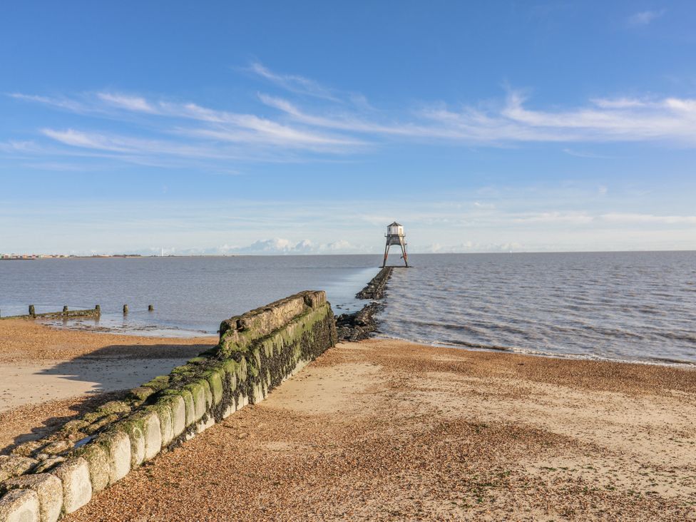 A view of a beach with a pier and lighthouse at Beachside Terrace in Harwich