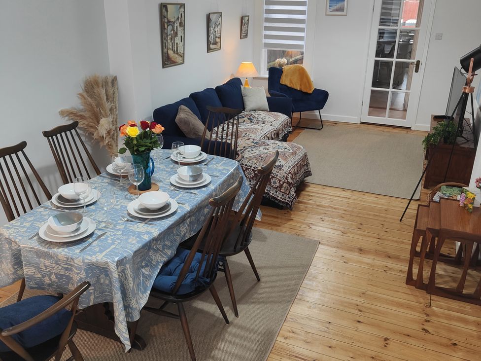 A dining room with a table set for dinner and a couch at Beachside Terrace in Harwich
