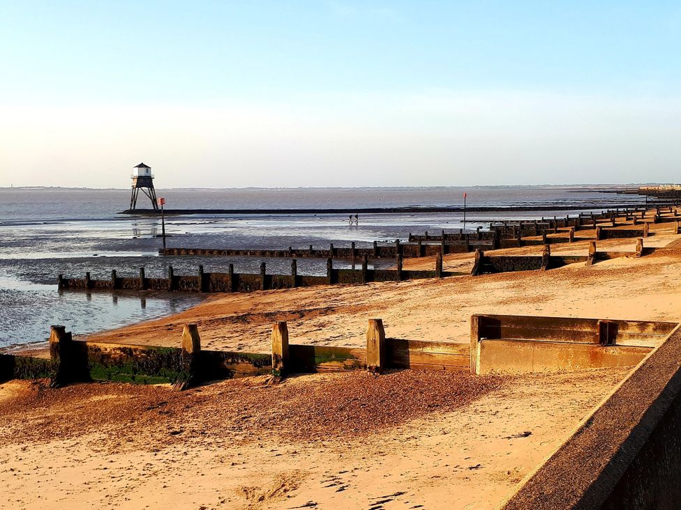 A beach scene with a lighthouse and jetty at Beachside Terrace Harwich