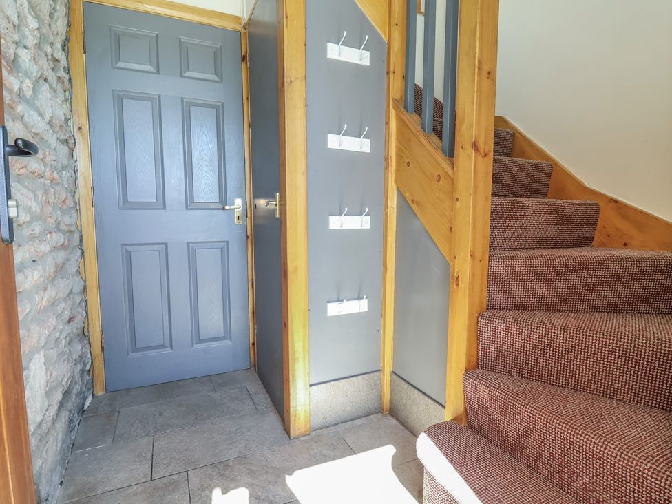 A hallway with a door and staircase at The Sun Inn Apartment in Mold