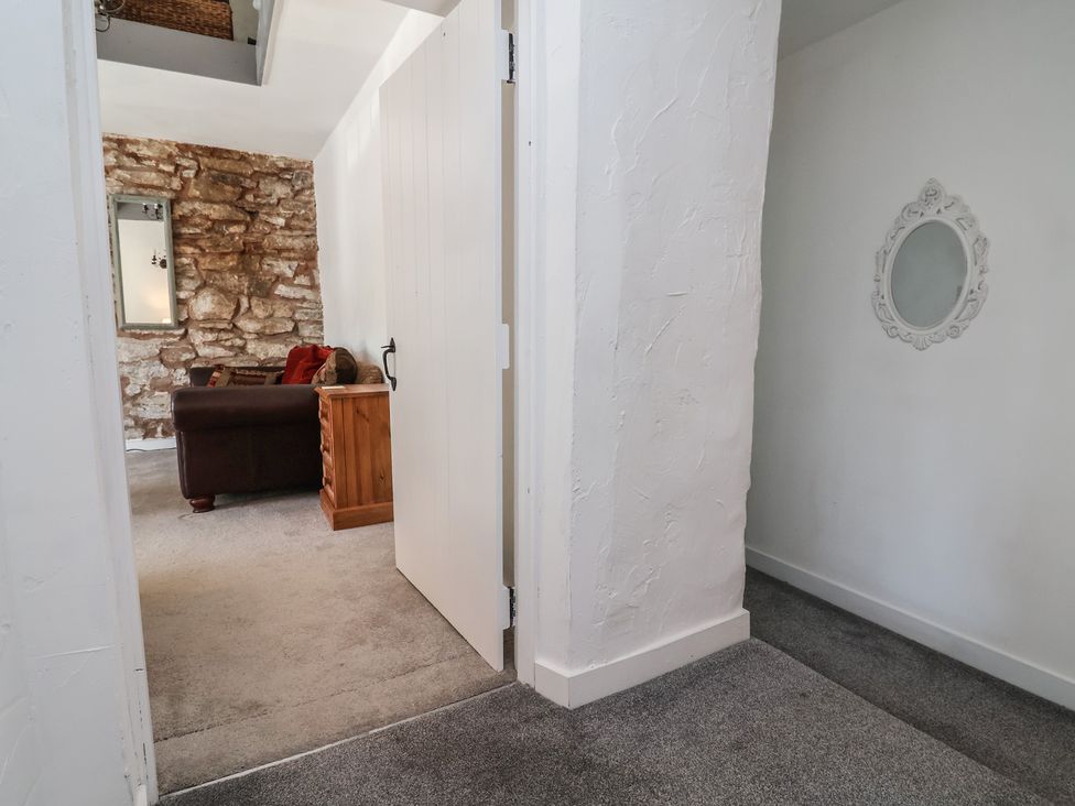 A living room with a couch and table visible through a door at The Sun Inn Apartment in Mold