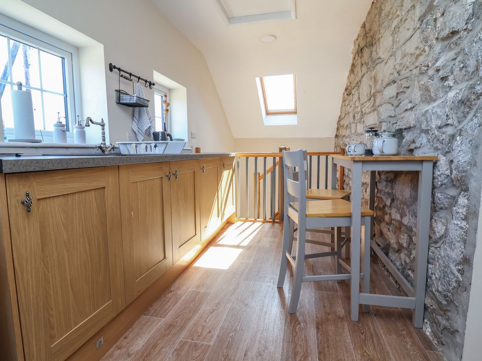 A kitchen with wooden cabinets and a bar table at The Sun Inn Apartment in Mold