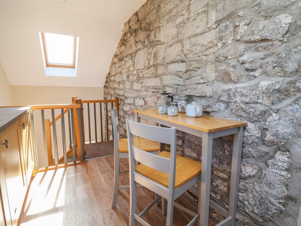 A snug with a table and chairs under a skylight at The Sun Inn Apartment in Mold