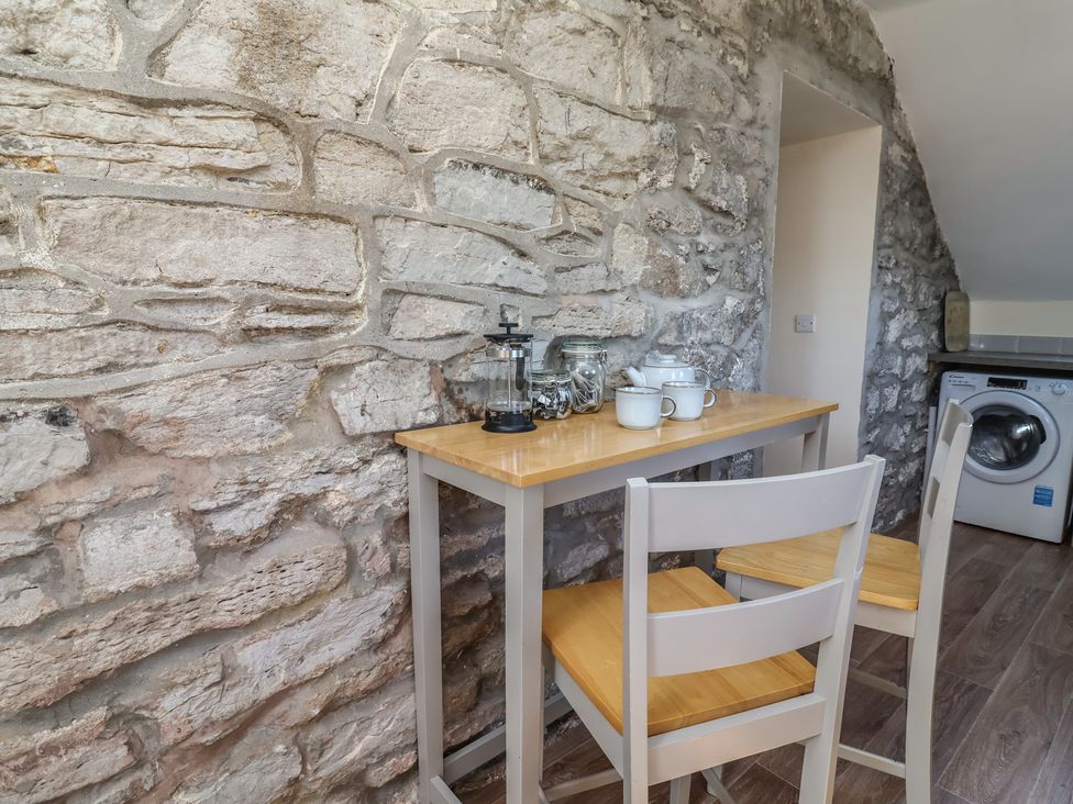 A kitchen with a table and chairs at The Sun Inn Apartment in Mold