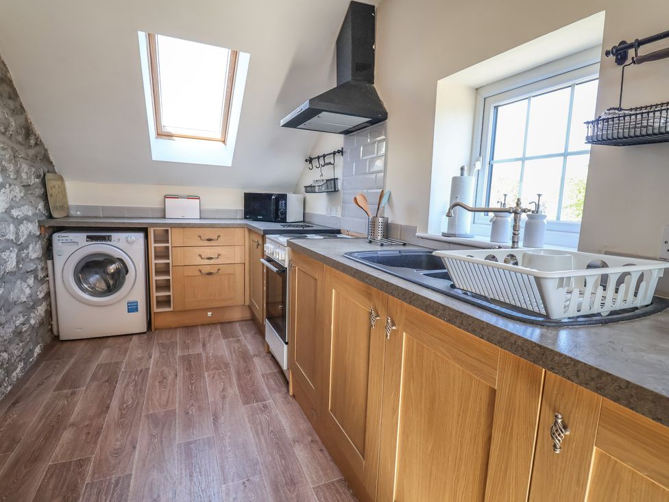 A kitchen with a washing machine and sink at The Sun Inn Apartment in Mold