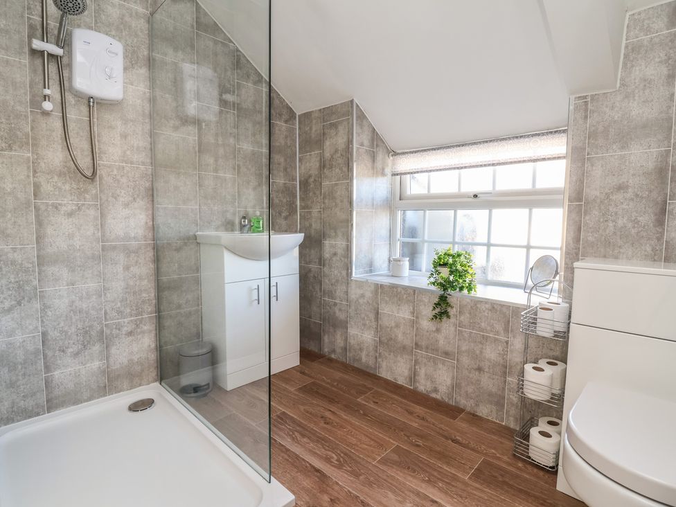 A bathroom with a shower, sink, and toilet at The Sun Inn Apartment in Mold