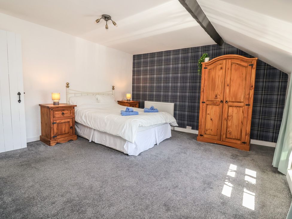 A bedroom with a bed and wooden furniture at The Sun Inn Apartment in Mold