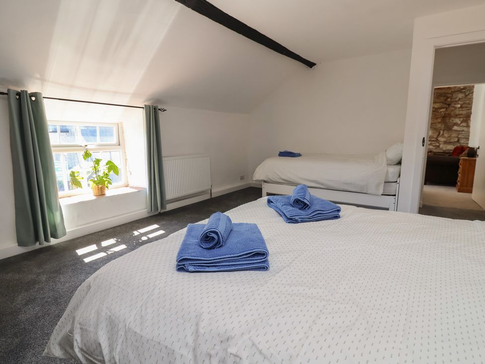 A bedroom with two beds and a plant at The Sun Inn Apartment in Mold