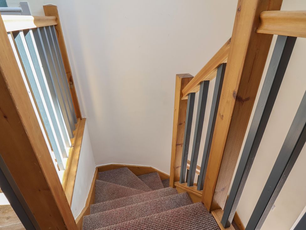 A staircase with wooden handrail and carpet at The Sun Inn Apartment in Mold
