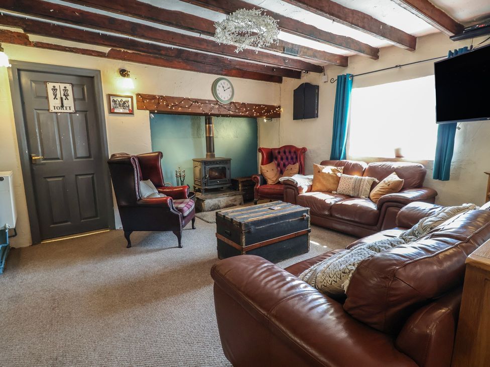 A living room with sofas and a wooden stove at The Sun Inn Apartment in Mold