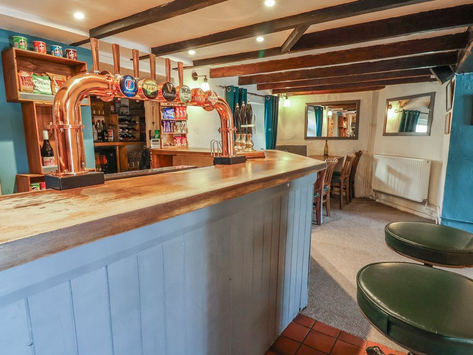 A bar area with beer taps and seating at The Sun Inn Apartment in Mold