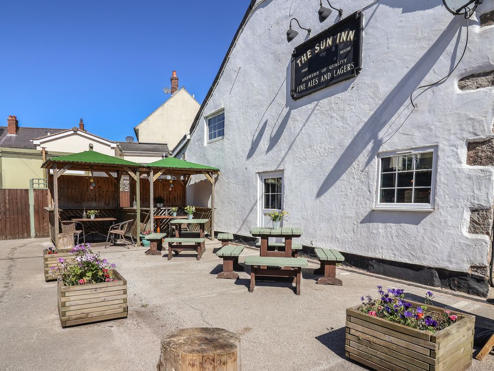 An outdoor seating area with tables and benches at The Sun Inn Apartment in Mold