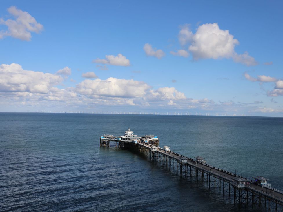 A pier extending over the ocean with wind turbines in the background at Upstairs at the Sun Inn Mold