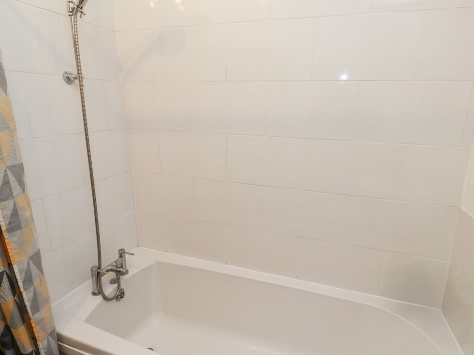 A bathtub with a showerhead and shower curtain at Chestnut Lodge in Bradford