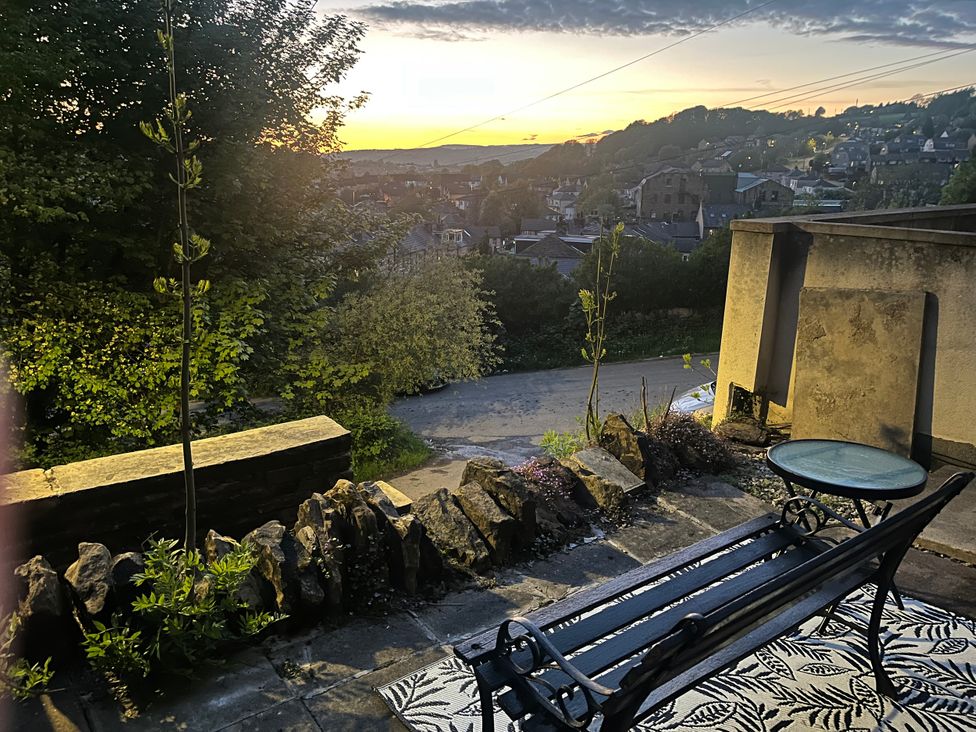 An outdoor area with a bench and table overlooking a village at Chestnut Lodge Bolton Woods near Shipley