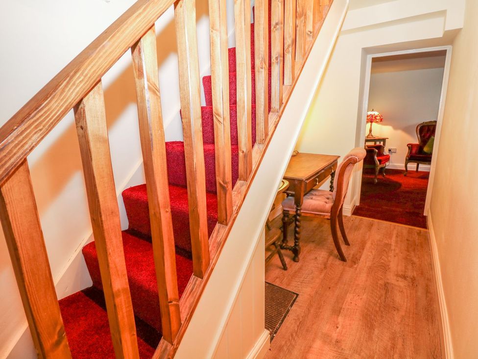 A staircase with a table and chair in a hallway at Little Bargate in Castleton, Peak District