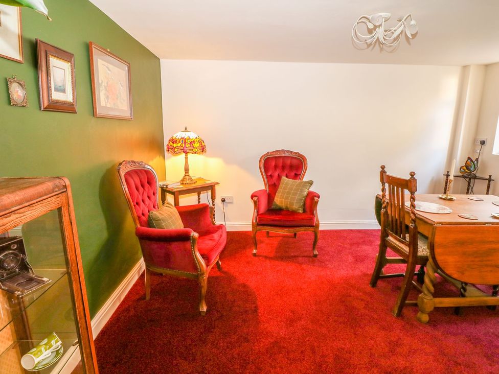A living room with red armchairs and a dining table at Little Bargate in Castleton, Peak District