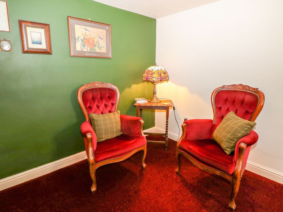 A snug with two chairs, a table, and a lamp at Little Bargate in Castleton, Peak District