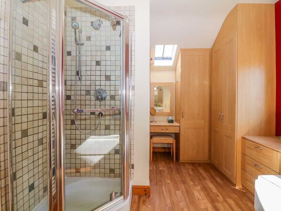 A bathroom with a shower, sink, and wooden cabinets at Little Bargate, Castleton, Peak District