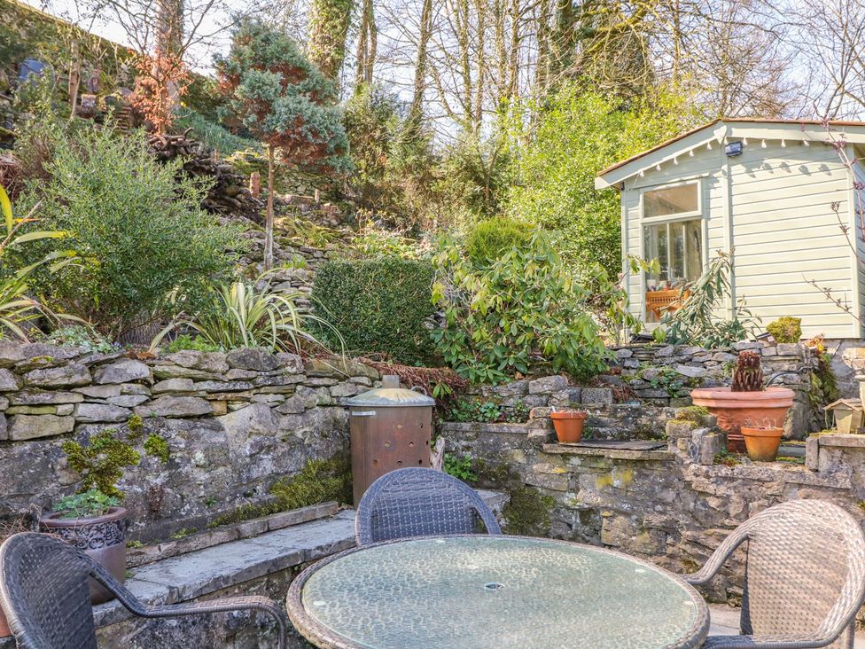 A garden with a table and chairs near a stone wall at Little Bargate in Castleton, Peak District