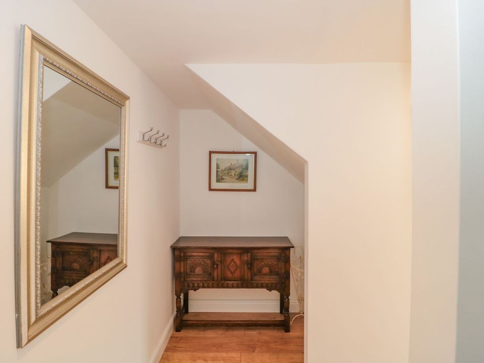 A hallway with a wooden table, mirror and wall hooks at Greenham Rise in Norton-Sub-Hamdon