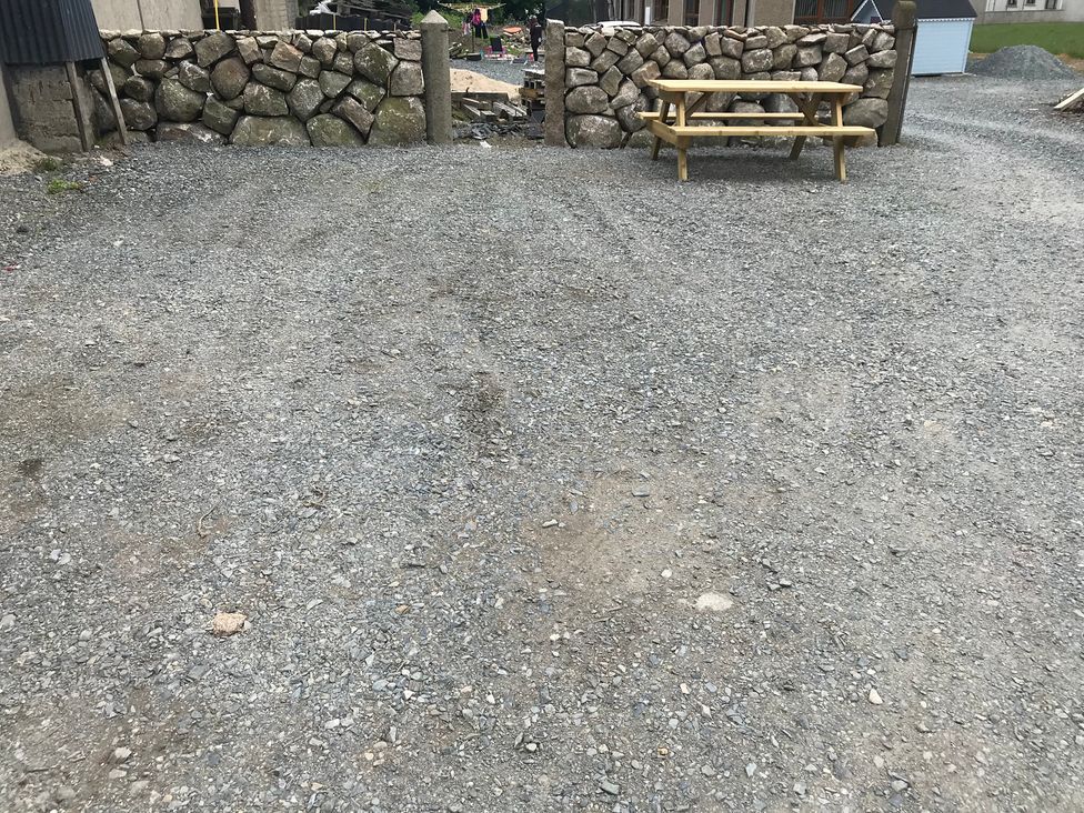 A gravel area with a rock wall and picnic table at 87 Ballyveaghmore Road in Newry