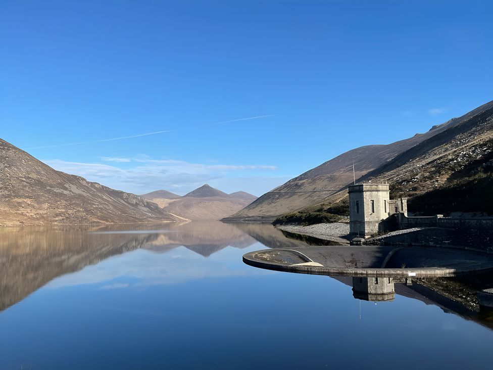 A lake surrounded by mountains with a building at 87 Ballyveaghmore Road Newry