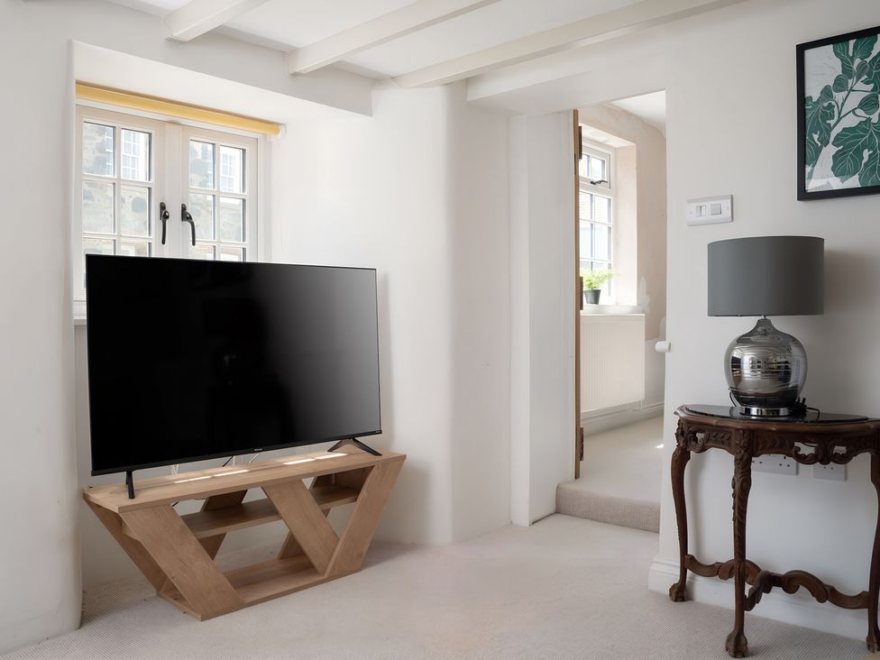 A living room with a television on a shelf at The Cottage in Helston