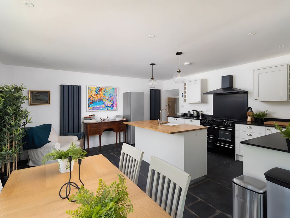A kitchen with a dining table and refrigerator at The Cottage in Helston