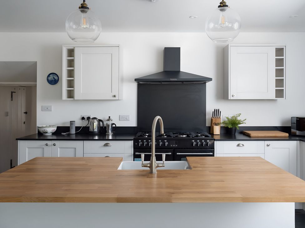 A kitchen with cabinets and a stove at The Cottage in Helston