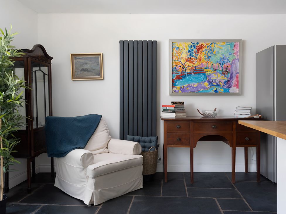 A living room with a chair and painting at The Cottage in Helston