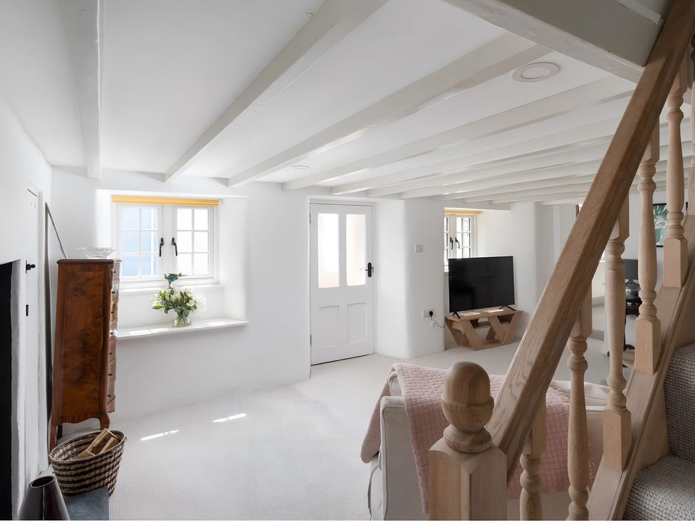 A living room with a television and a staircase at The Cottage in Helston