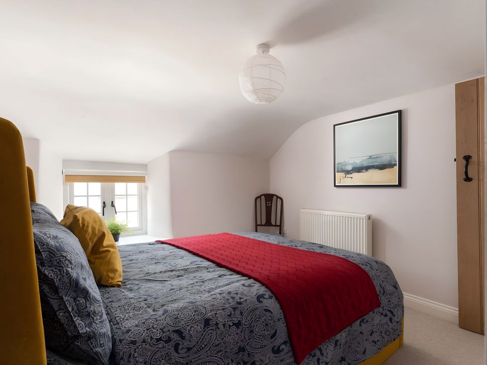 A bedroom with a bed and window at The Cottage in Helston