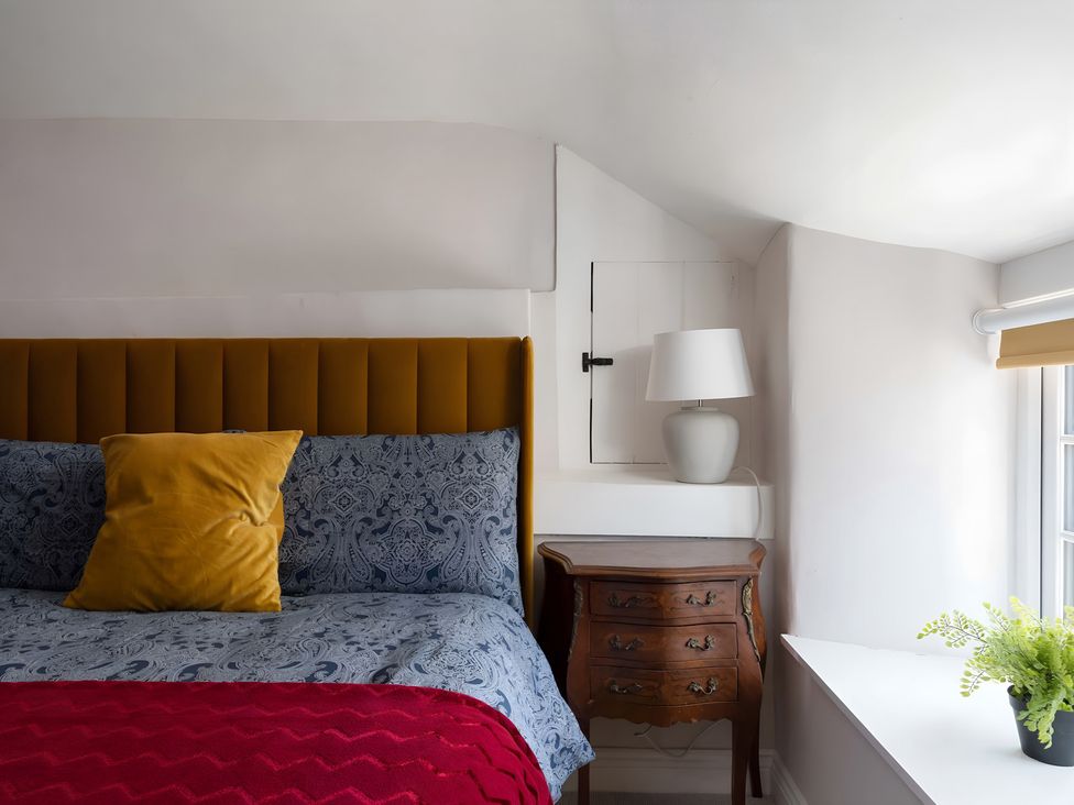 A bedroom with a bed and lamp at The Cottage in Helston