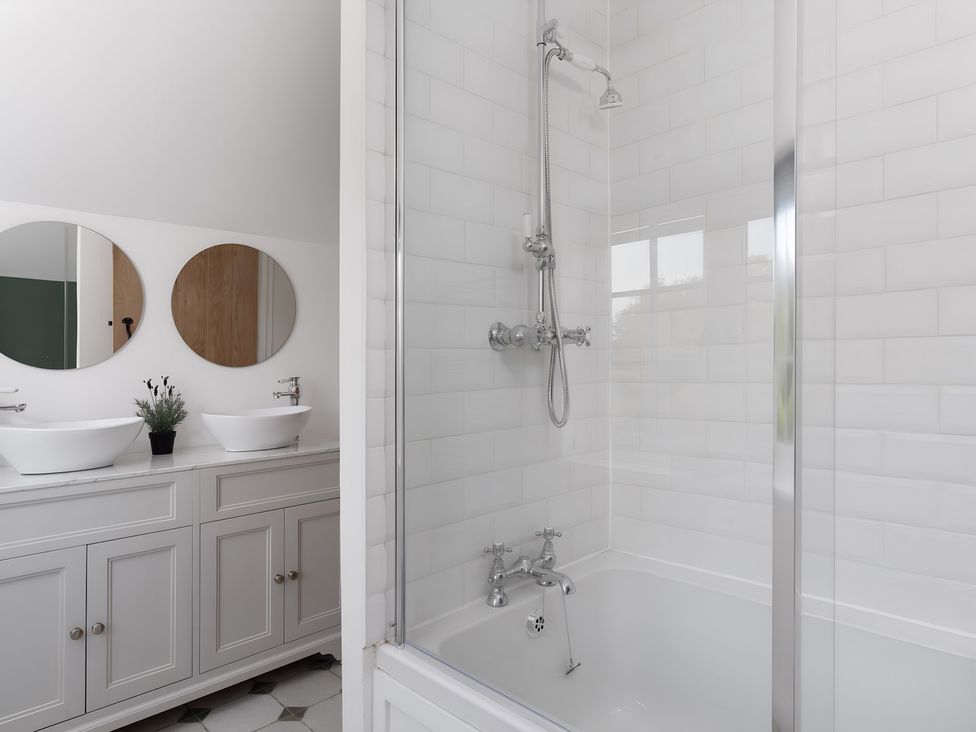 A bathroom with a shower and two hand basins at The Cottage in Helston