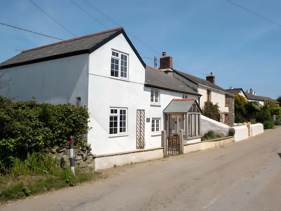 A house with white walls and a gate at The Cottage in Helston