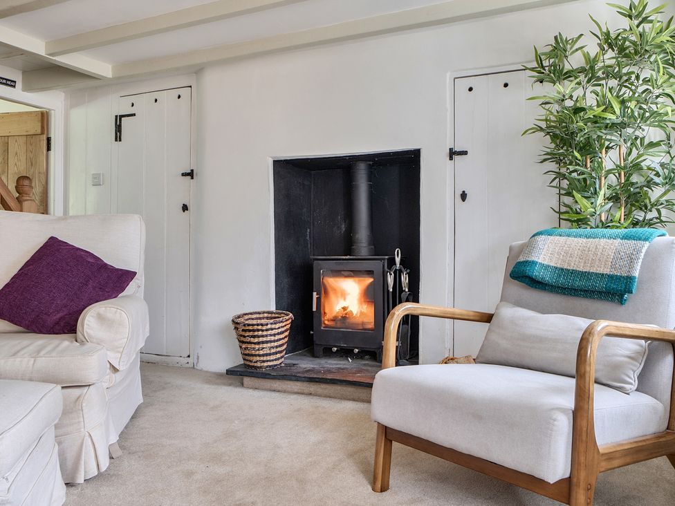 A living room with a fireplace and seating at The Cottage in Helston