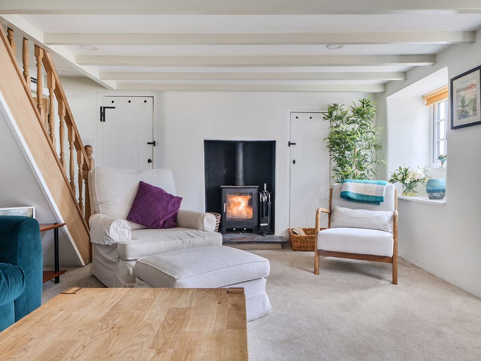 A living room with a fireplace and armchair at The Cottage in Helston