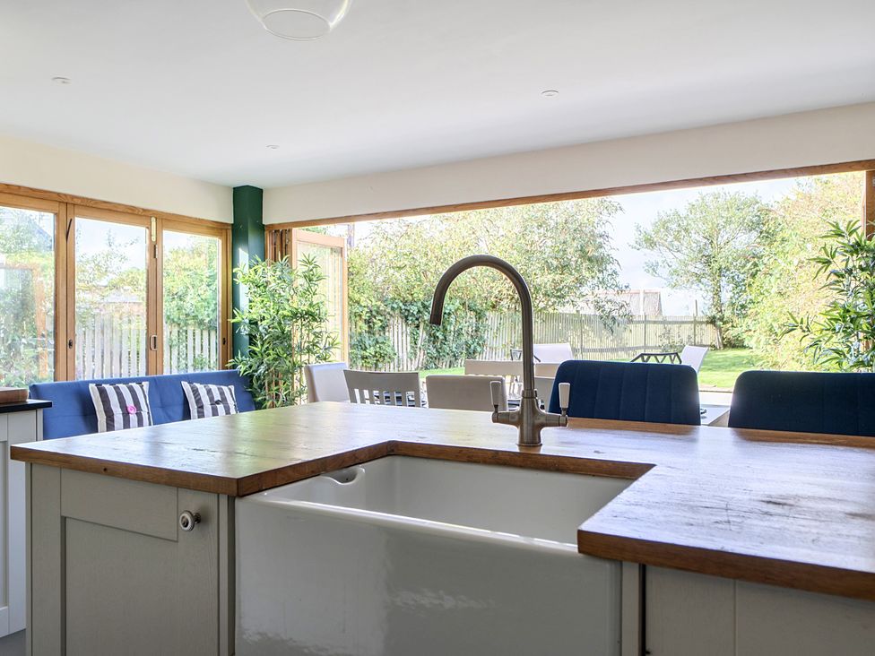 A kitchen with a sink and bar stools at The Cottage in Helston