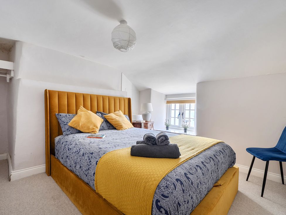 A bedroom with a bed and window at The Cottage in Helston