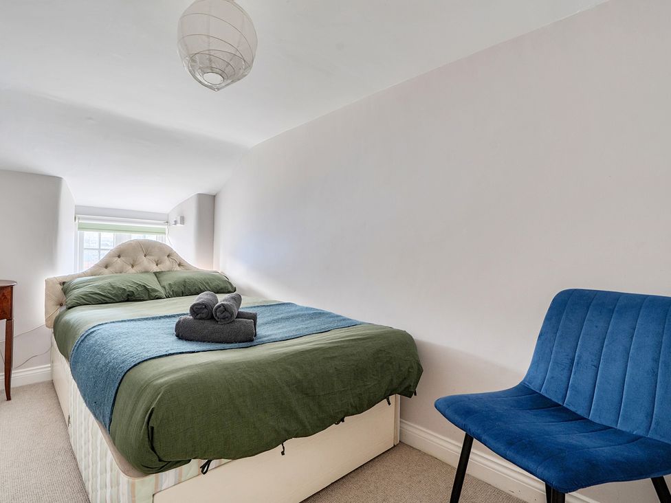 A bedroom with a bed and chair at The Cottage in Helston