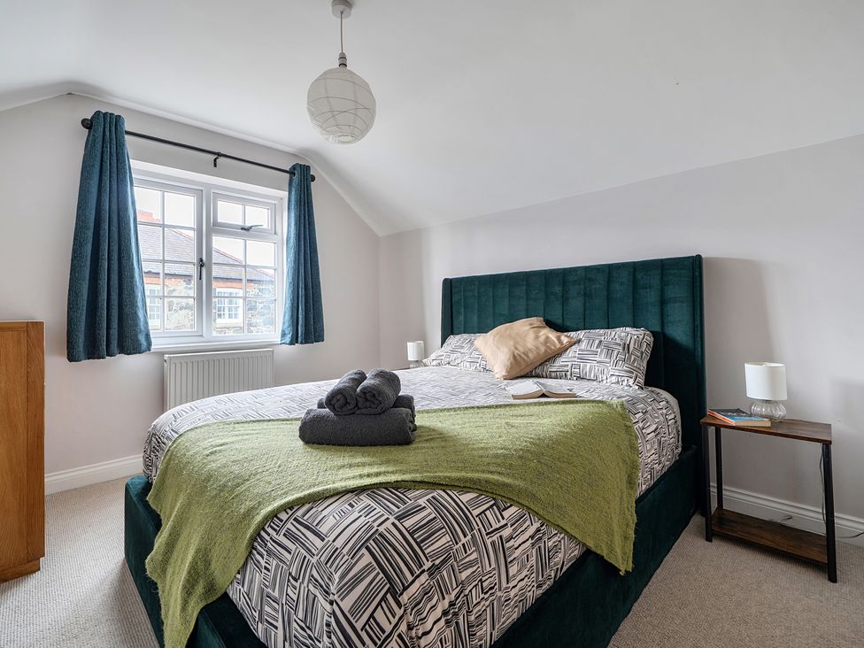 A bedroom with a bed nightstand and curtains at The Cottage in Helston