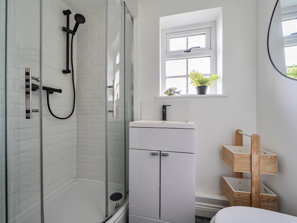 A bathroom with a shower, sink, and storage at The Cottage in Helston