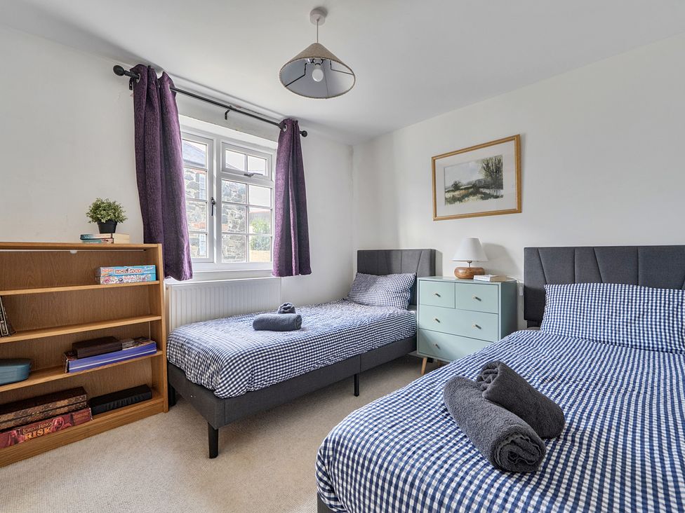 A bedroom with two beds and a shelf at The Cottage in Helston