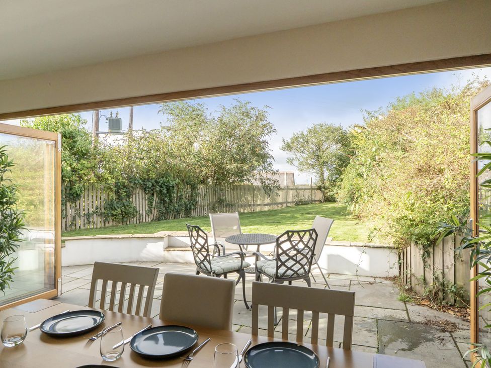 A dining room with an open view to a garden at The Cottage in Helston