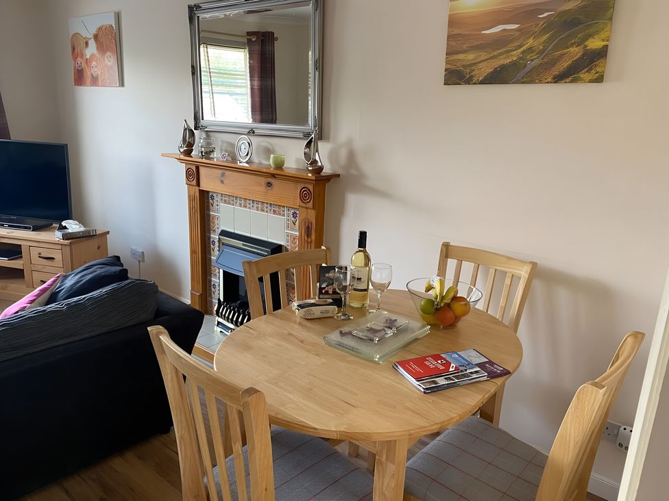 A living room with a table and chairs and a fireplace at 9 Creag An Iolaire near Portree