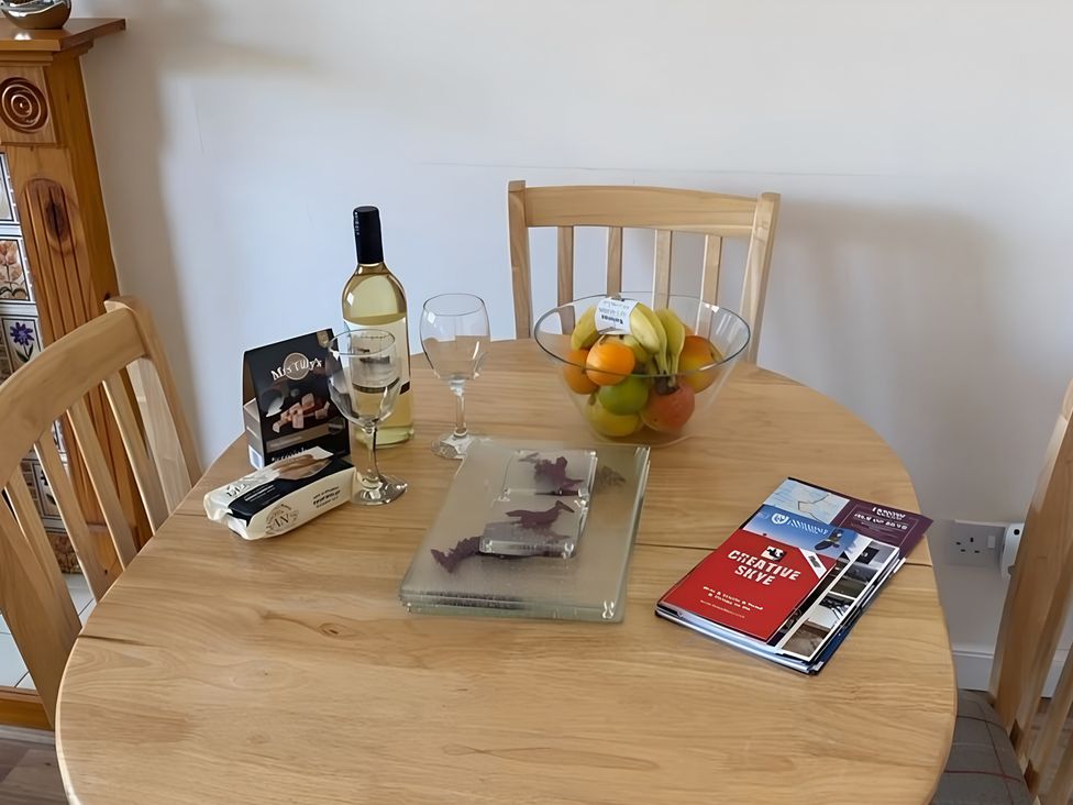 A dining table with a wine bottle and fruit bowl at 9 Creag An Iolaire Near Portree